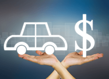 Two hands one holding up a white outline of a car the other holding up a white outline of a dollar sign