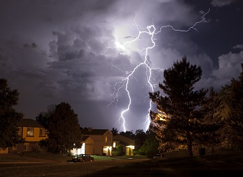 Lightning flashing in the sky during a storm above a neighborhood